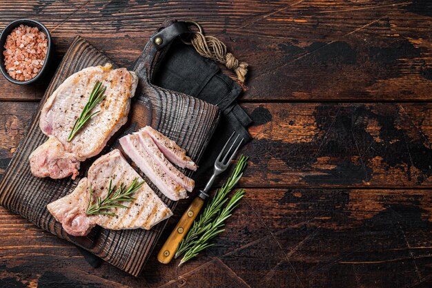 BBQ gegrillte Schweinekotelettsteaks oder Koteletts, die auf Holzschneidebrett geschnitten werden Holzhintergrund Ansicht von oben Kopieren Sie Platz