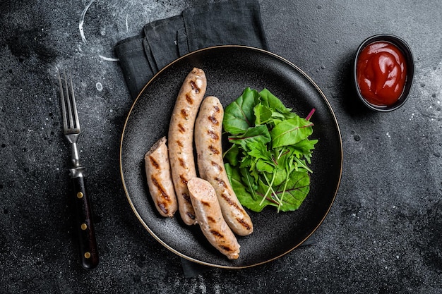 BBQ Gegrillte Würstchen aus Schweinefleisch, serviert mit Gemüse Schwarzer Hintergrund Draufsicht