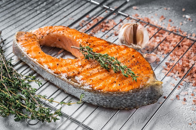 BBQ gegrilltes Lachs-Fisch-Steak auf einem Grill mit Thymian und rosa Salz. Weißer Hintergrund. Ansicht von oben