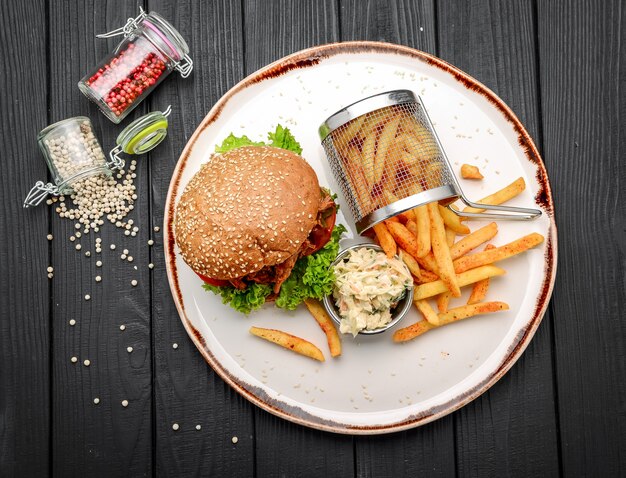 Foto bbq geräuchertes pulled pork sandwich mit gurken. auf einer schwarzen holzoberfläche