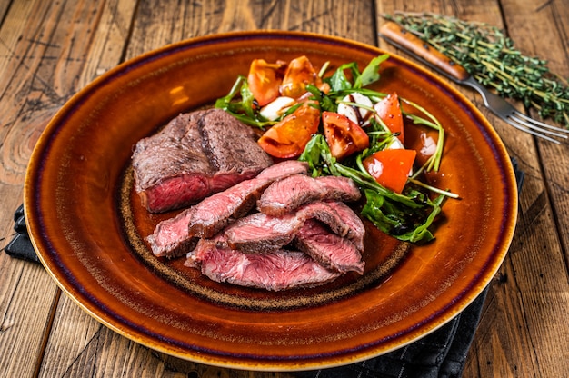 BBq Oyster Top Blade assado ou bife de rosbife em um prato com salada. Mesa de madeira. Vista do topo.