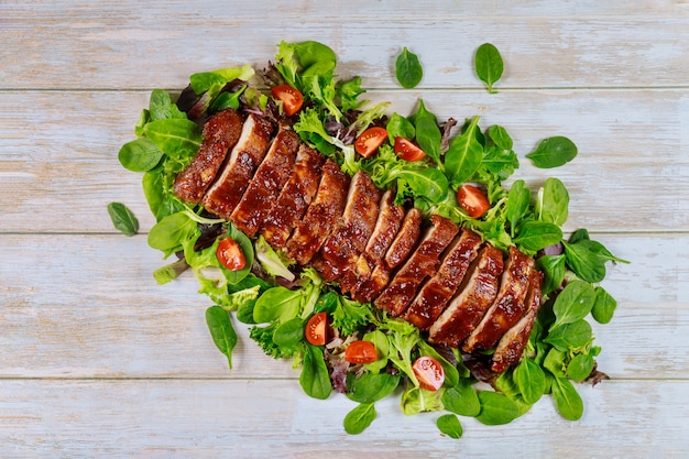 BBQ Schweinefilet auf grünen Blättern mit Tomate.