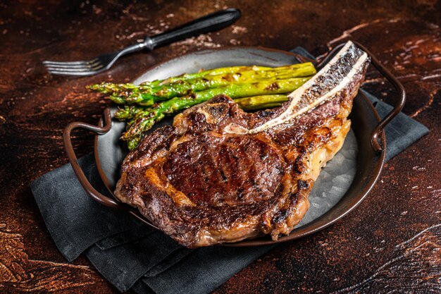 BBQ Tomahawk a la parrilla o vaquero con bistec de carne de hueso espárragos asados Fondo de madera Vista superior