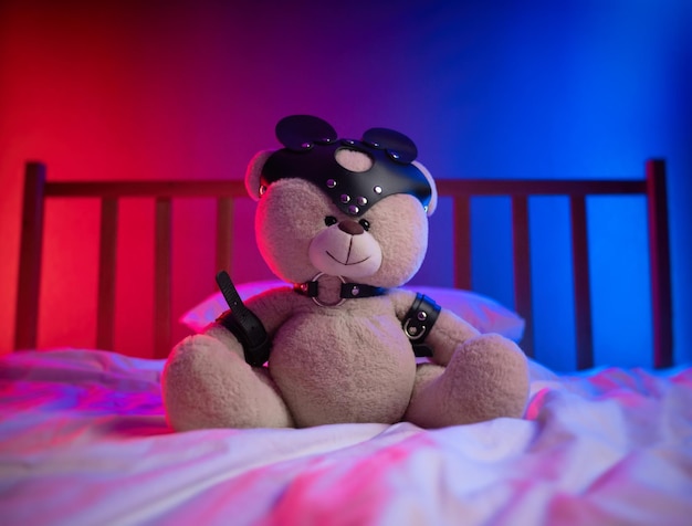 Bdsm-Riemen für Sexspiele an einem Teddybären im Neonlicht auf dem Bett