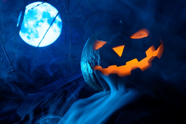 Beängstigender Halloween-Kürbis mit leuchtendem Gesicht mit Vollmond im Nebel