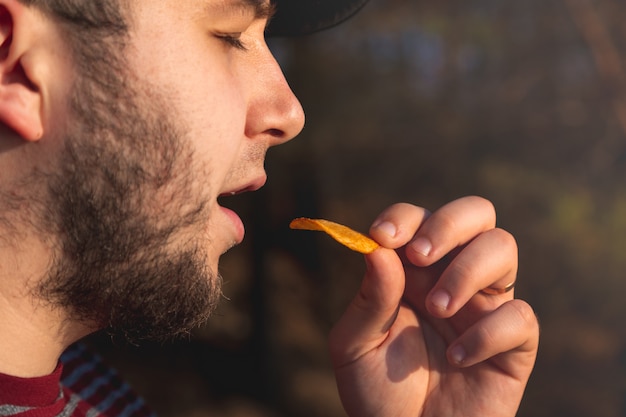 Bearder Hombre en el bosque comiendo patatas fritas. En la imagen del parque al aire libre con borrosa