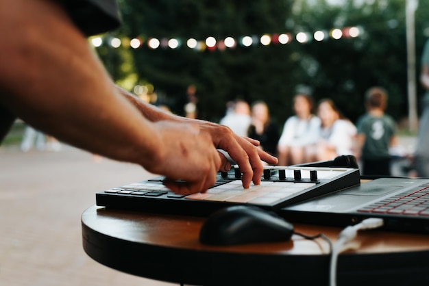 Beatmaker de músico tocando em um controlador eletrônico de bateria eletrônica no festival de música de rua closeup foco seletivo no controlador midi e mão