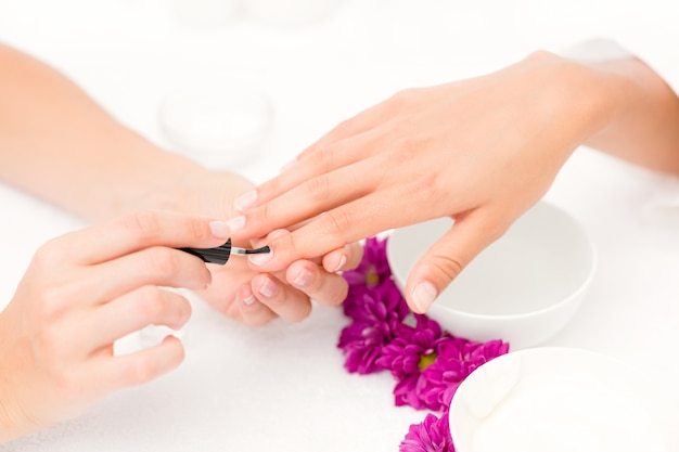 Beautician aplicando verniz de unhas para clientes femininos unhas