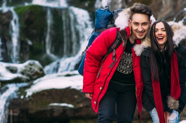 Beautiful smiling hipster casal de pé em uma rocha, montanhas, cachoeiras, sorriso benevolente dois caras na expedição de aventura de montanha, moda par de diversão ao ar livre