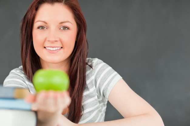 Foto beautilful mujer joven que muestra una manzana con la cámara se centran en el modelo