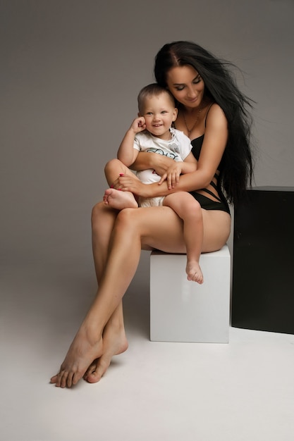 Beautiuful mujer caucásica se sienta en un cubos blancos y negros y abraza a su hijo, imagen en blanco