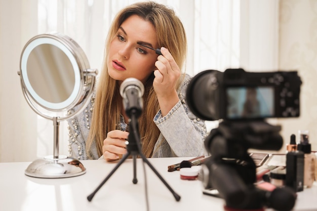 Beauty-Bloggerin verwendet Augenbrauen-Tönungsgel während der Videoaufnahme für ihre Follower