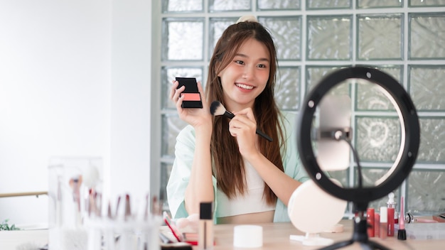 Beauty-Influencer-Konzept Junge Frau trägt Rouge auf, um Produkt vorzustellen und Video für Vlog aufzunehmen