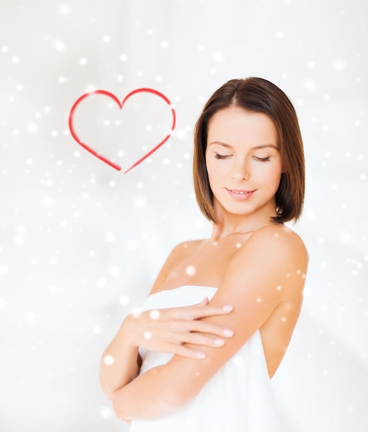 Beauty-, Spa- und People-Konzept - schöne Frau, die im Handtuch über schneebedecktem Hintergrund steht