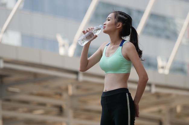 Beba agua después del entrenamiento, concepto de la ciudad del deporte de la mujer del deporte.