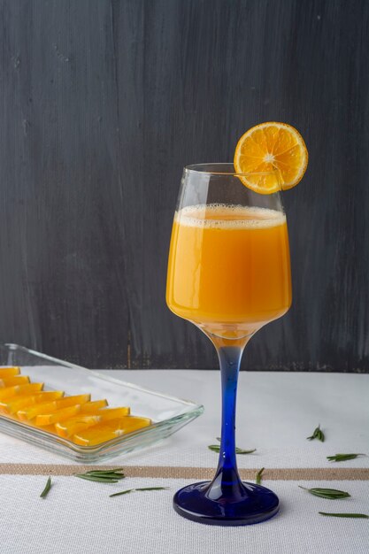 Beba com suco de laranja e água mineral com algumas flores e rodelas de laranja em um prato