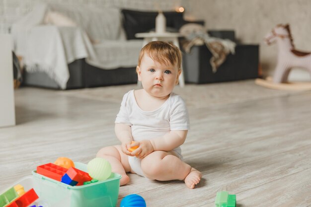 Bebé de 69 meses jugando con una colorida pirámide de juguete del arco iris sentado en un dormitorio blanco y soleado Juguetes para niños pequeños Interior infantil Un niño con un juguete educativo