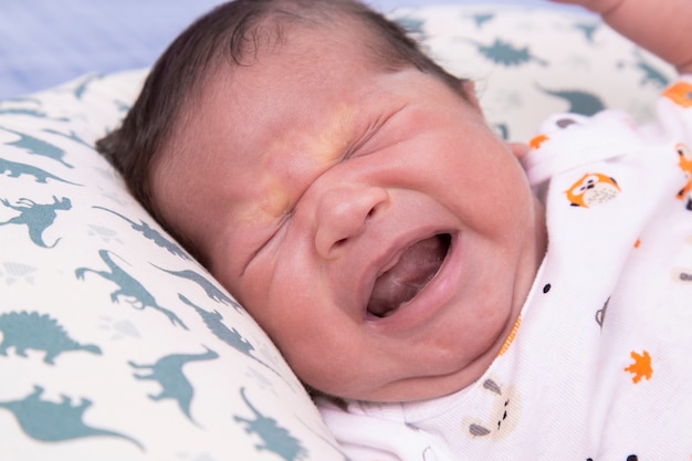 Bebê acordando e chorando na cama.