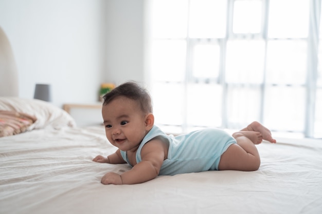 Bebé acostado boca abajo jugando en la cama