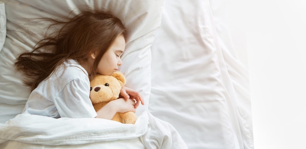 Bebé acostado en la cama con taddy bear niña duerme con juguete tejido