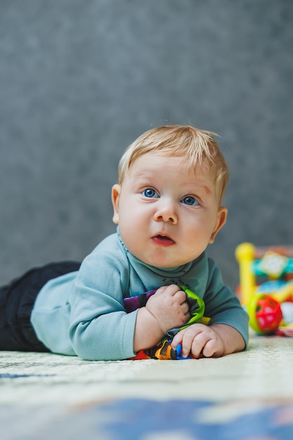 El bebé se acuesta en una alfombra térmica y juega Selfdevelopment de un recién nacido Juguetes para el desarrollo del niño