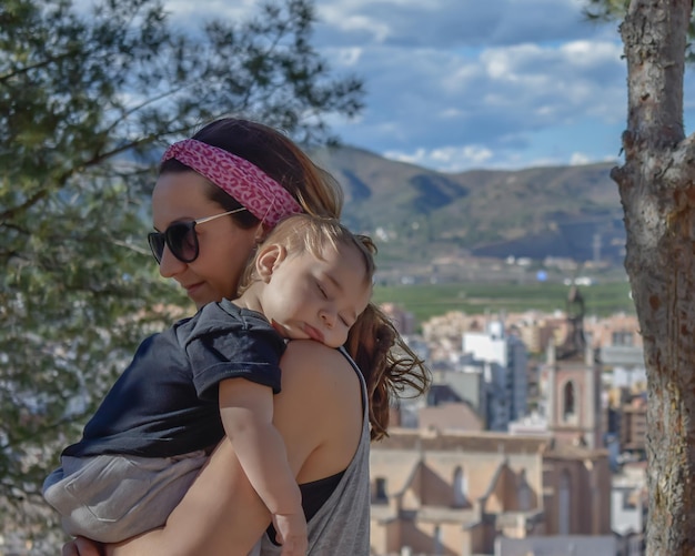 El bebé acurrucado en los brazos de la madre en las ruinas del verano