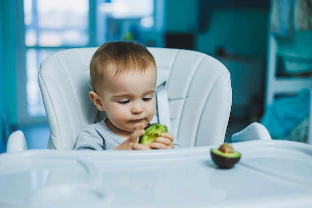 Bebê adorável comendo abacate Vitamina e comida saudável para crianças pequenas Retrato de uma linda criança de 8 meses