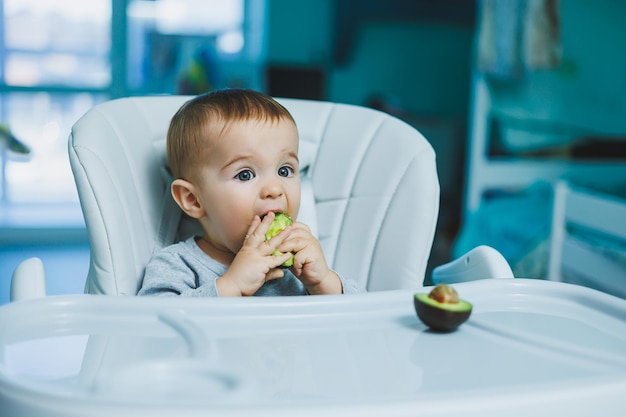 Bebê adorável comendo abacate Vitamina e comida saudável para crianças pequenas Retrato de uma linda criança de 8 meses