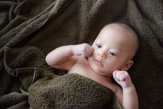 Bebé adorável sob uma toalha com capuz após o banho