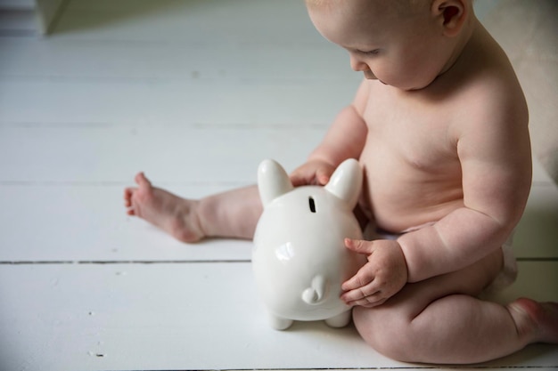 Un bebé aferrándose a una alcancía costo de criar a un niño concepto