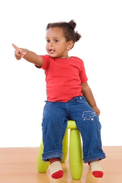 Bebé africano sentado en un taburete sobre un fondo blanco
