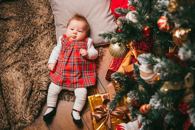 Bebé al lado del árbol de navidad