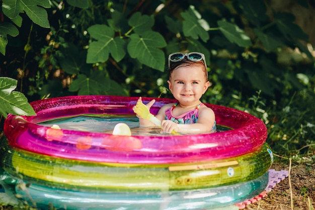 Bebé alegre disfrutando de su día en sumer en su piscina con pala de plástico