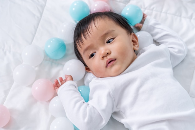 Foto bebê alegre jogando bola colorida na cama