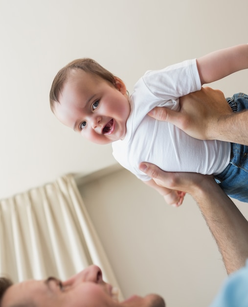 bebé alegre llevado por el padre