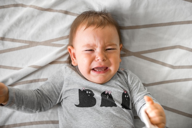 Bebé de un año llorando en la cama.