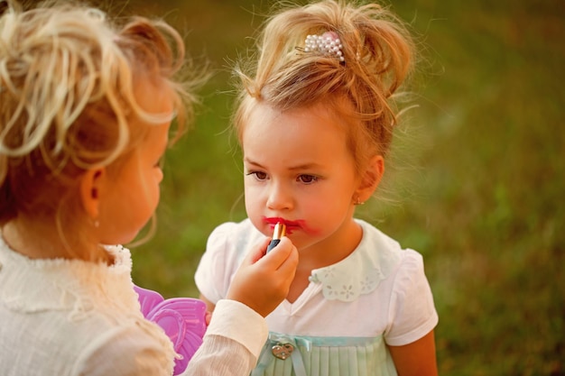 El bebé aplica lápiz labial rojo en los labios del modelo infantil.