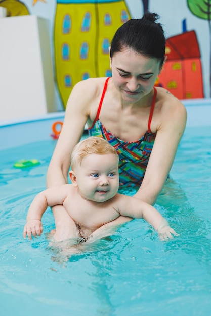 Un bebé aprende a nadar en una piscina con un entrenador Un bebé aprende a nadar Desarrollo del niño