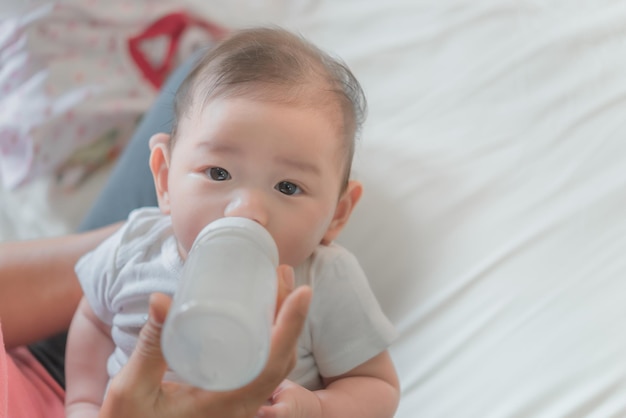 Bebé asiático bebe leche del biberón para ir a la cama