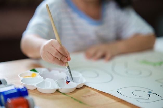 Bebê asiático bonitinho sorrindo pintura com tintas coloridas usando aquarela Menina asiática usando pincel desenho cor Conceito de estilo de vida de atividade de bebê