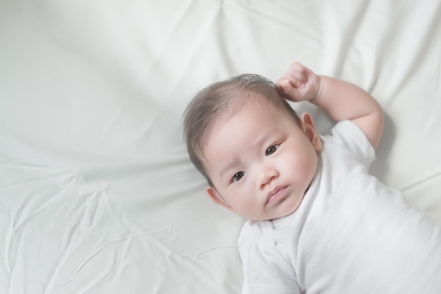 Bebê asiático closeup deitado na cama menina bonitinha da tailândia