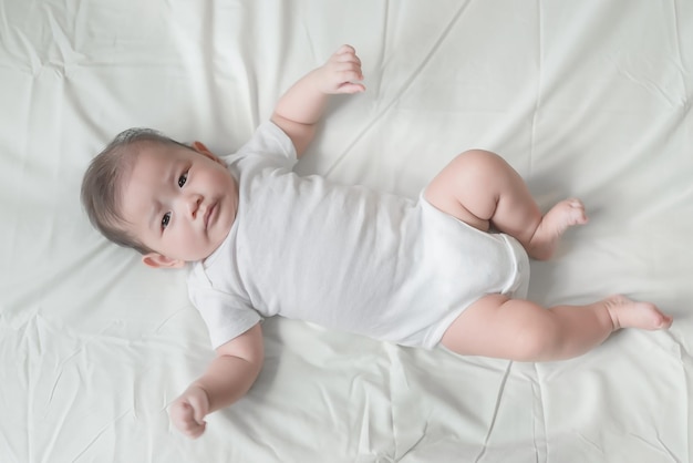 Bebê asiático closeup deitado na cama Menina bonitinha da Tailândia