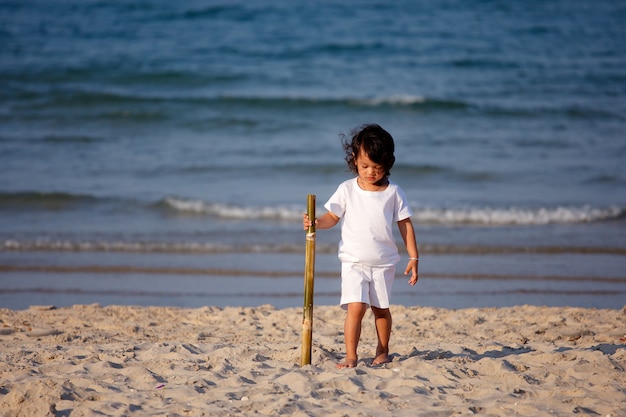 Bebé asiático joven caminando en la playa tropical