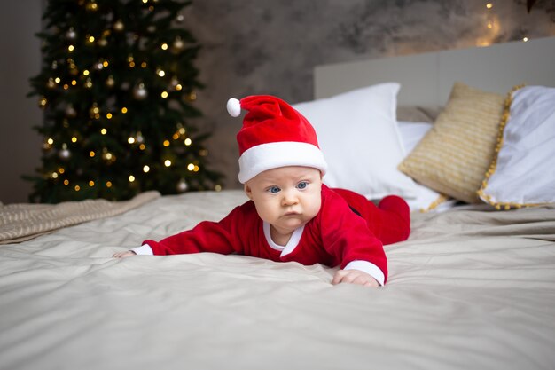 Bebé atractivo en traje de Navidad en casa