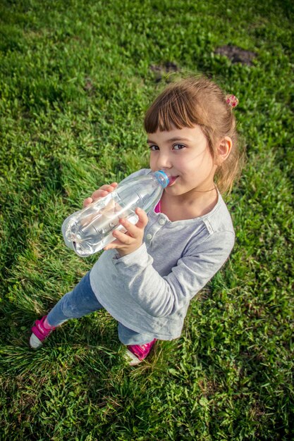 El bebé bebe agua del enfoque selectivo de la botella