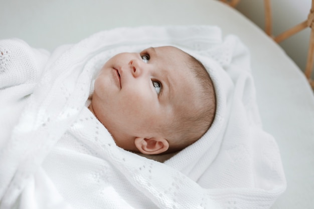 Bebé en blanco dormitorio soleado bebé recién nacido está descansando en la cama