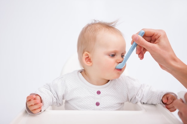 Bebê bonito comendo enquanto está sendo acompanhado por sua mãe