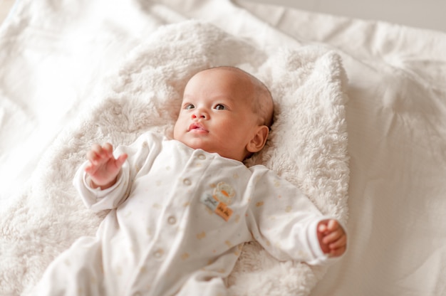 Bebé bonito em um quarto da luz branca O bebê recém-nascido é bonito.