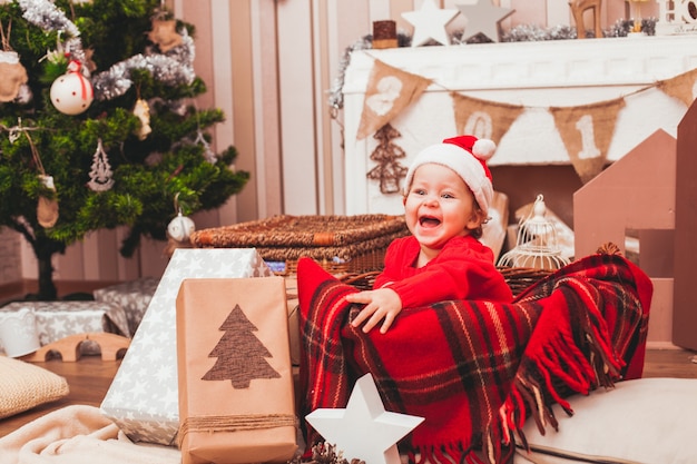 Bebé bonito feliz vestido con traje de Santa Claus con regalos de Navidad