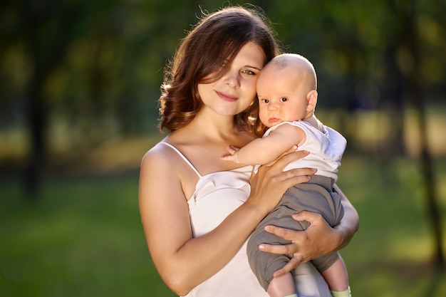 Bebé en brazos de una joven encantadora en el parque
